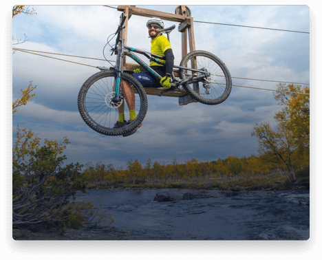 iFit Trainer Casey Zaugg riding a bike lift over a river in Norway.