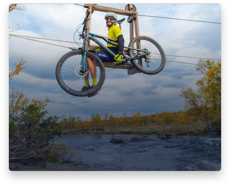 iFit Trainer Casey Zaugg riding a bike lift over a river in Norway.