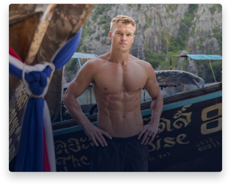 iFit Trainer John Peel standing in front of a boat in Thailand.