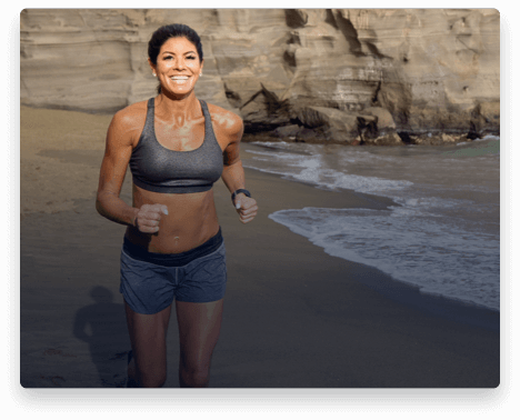 iFit Trainer Stacie Clark running on a beach in Hawaii.